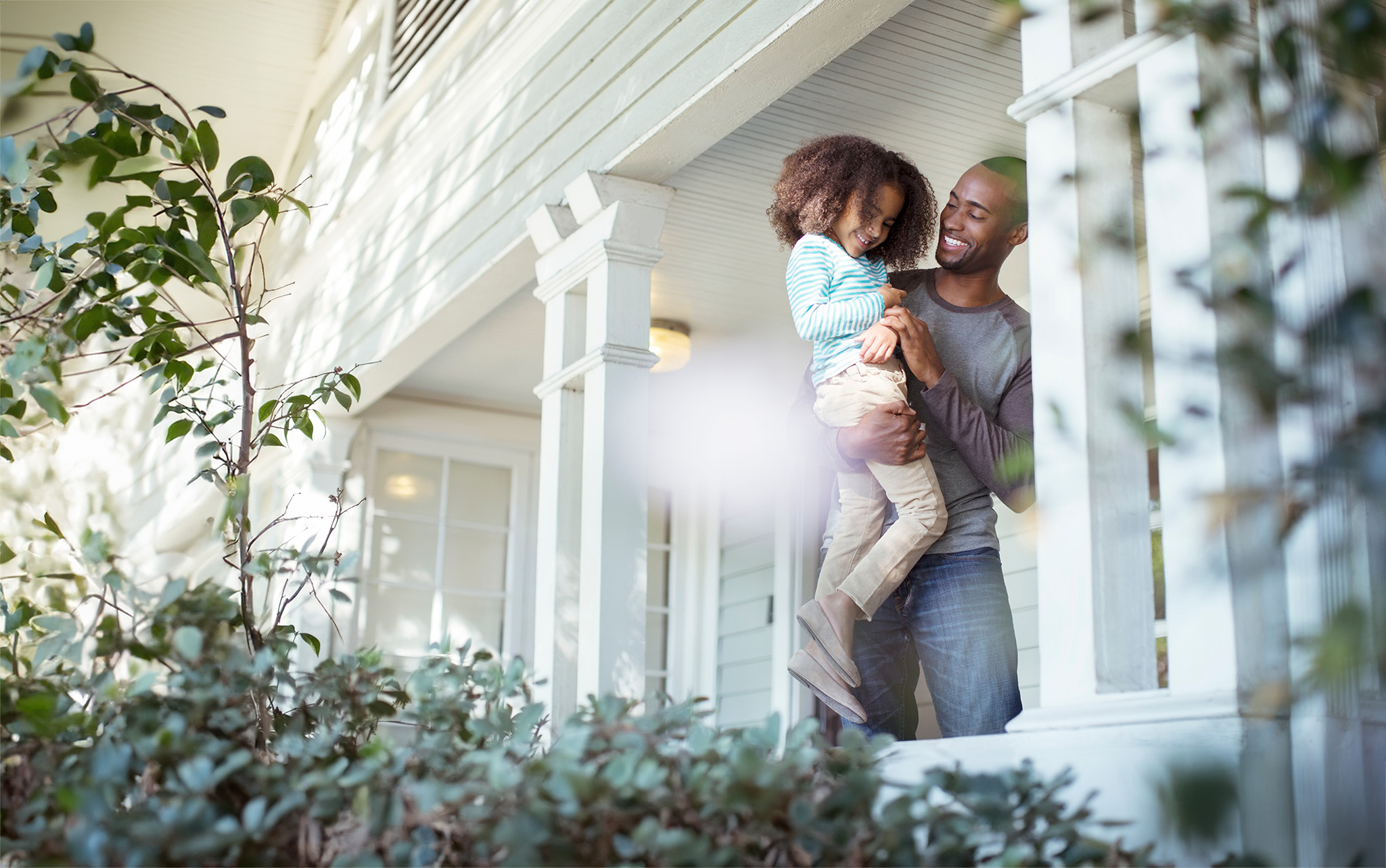 Father holding daughter in their front yard.